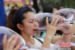 图为参赛选手拿着巨型酒杯喝红酒比赛。　杨孝永 摄 - 重庆晨网