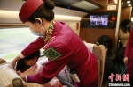 在成都东开往沙坪坝的G8607次列车上，“列车妈妈”雷涛为正在哺乳的旅客戴哺乳巾。　陶静 摄 - 重庆晨网